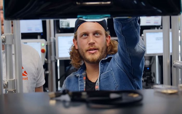 Falk schaut auf einen Monitor an einem Regal.